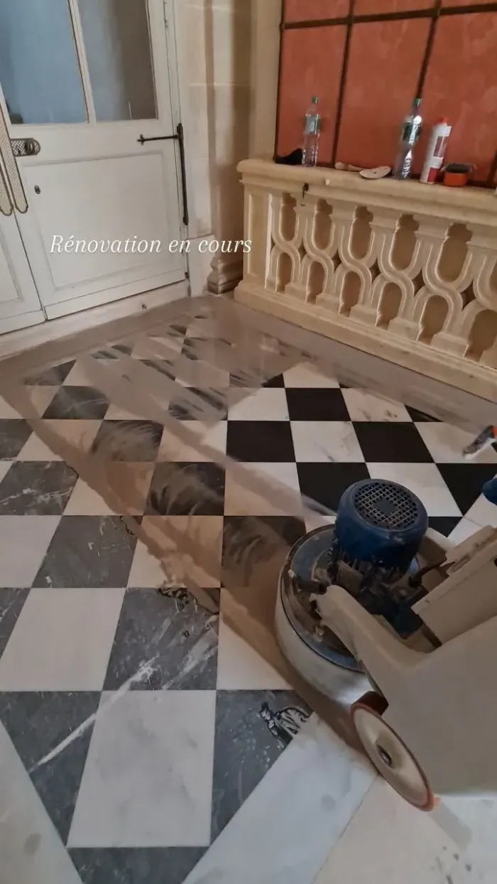 Artisan ponçant un sol en marbre en damier à Versailles avec une monobrosse italienne.